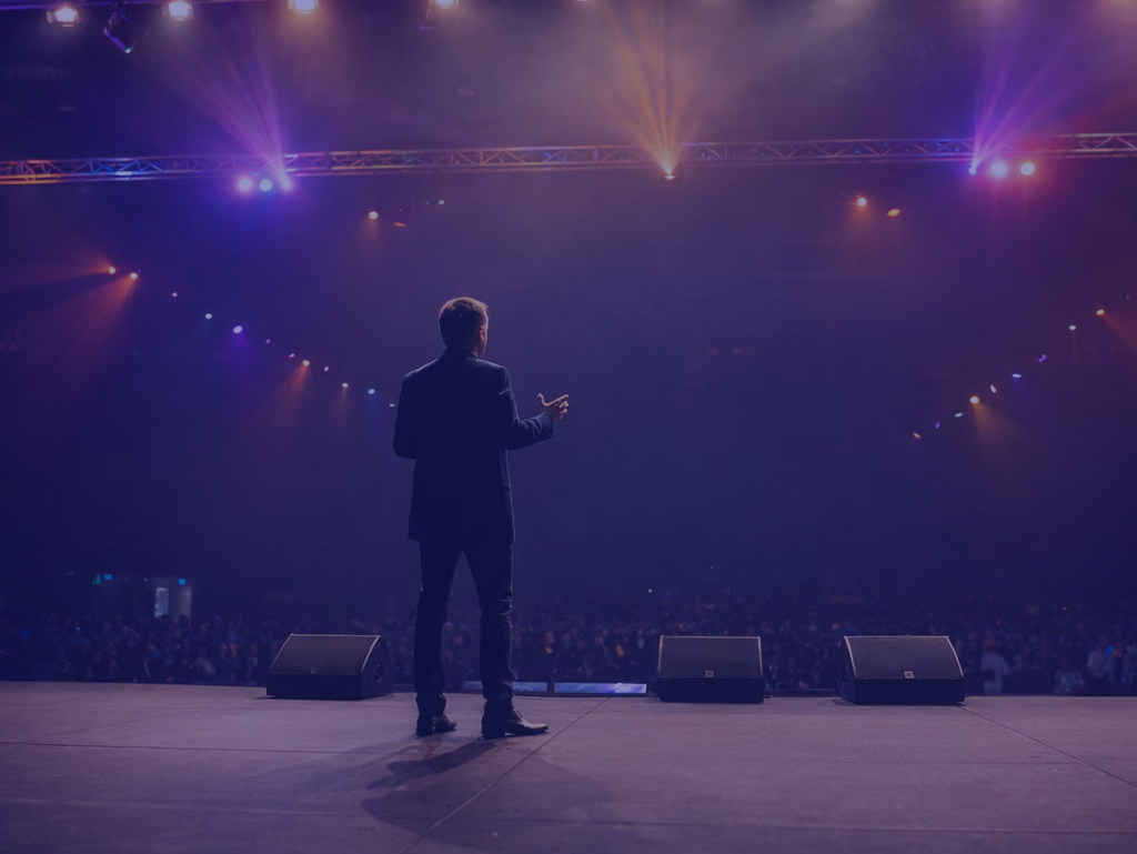 backshot speaking to audience from stage