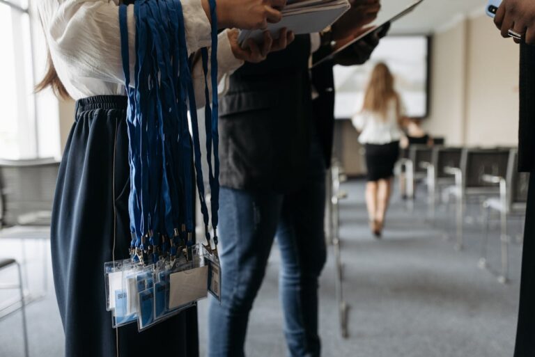 Conference staff holding many lanyards ready to hand out as the audience arrives at the event.